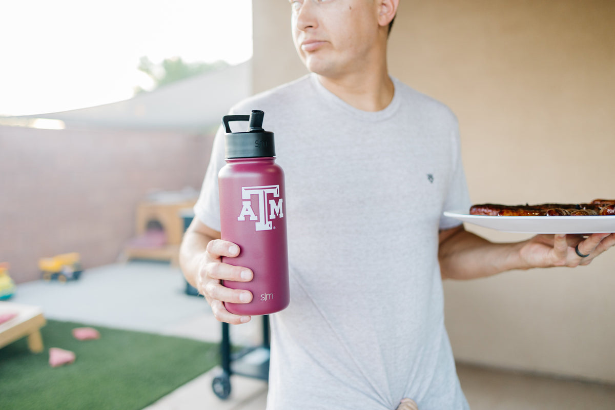 Man in light gray t-shirt holding burgundy water bottle against soft beige background