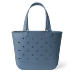 Soft blue-gray tote bag with dark charcoal perforations, neutral color in muted slate tone.